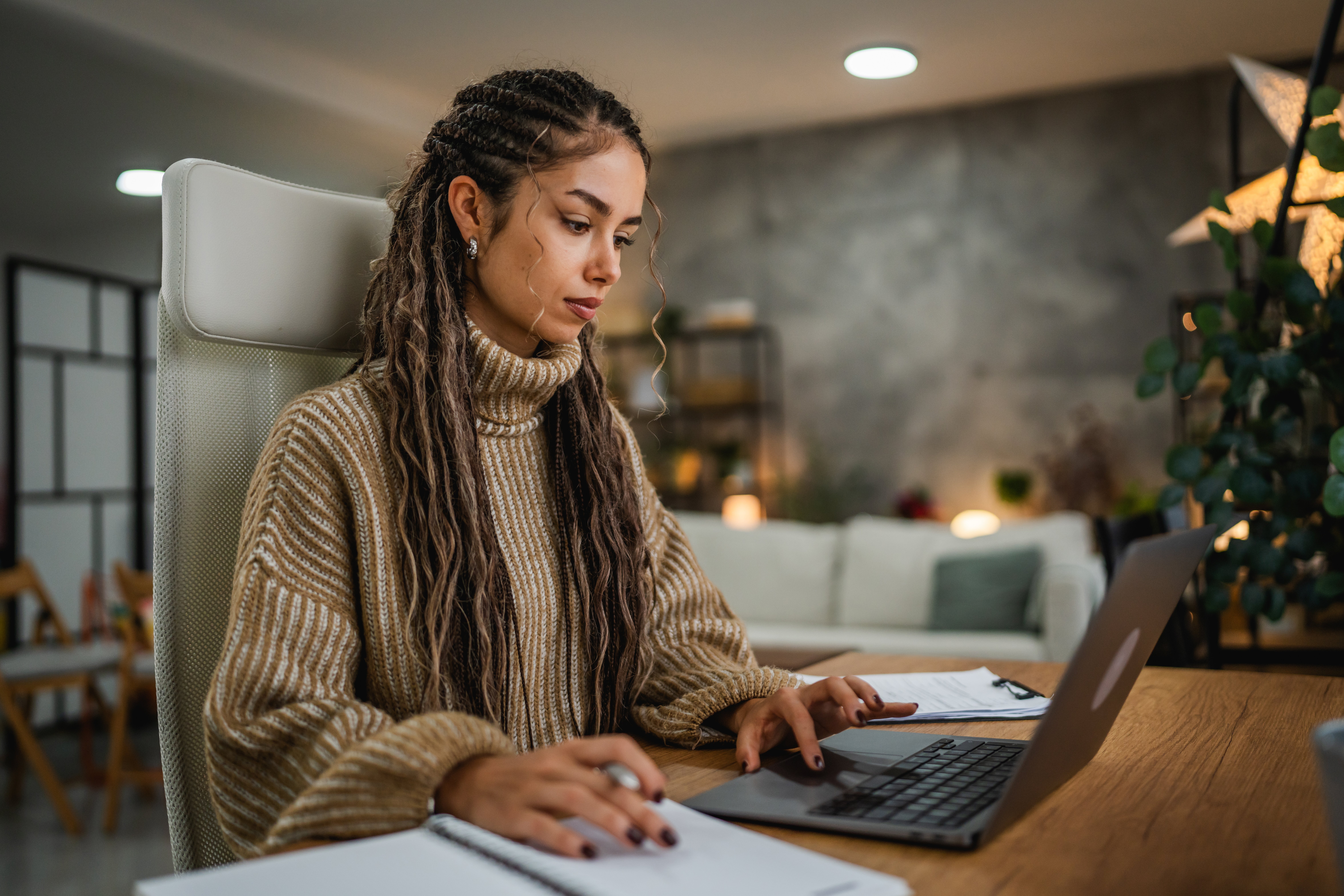 Frau arbeitet am Laptop und schreibt gleichzeitig Notizen