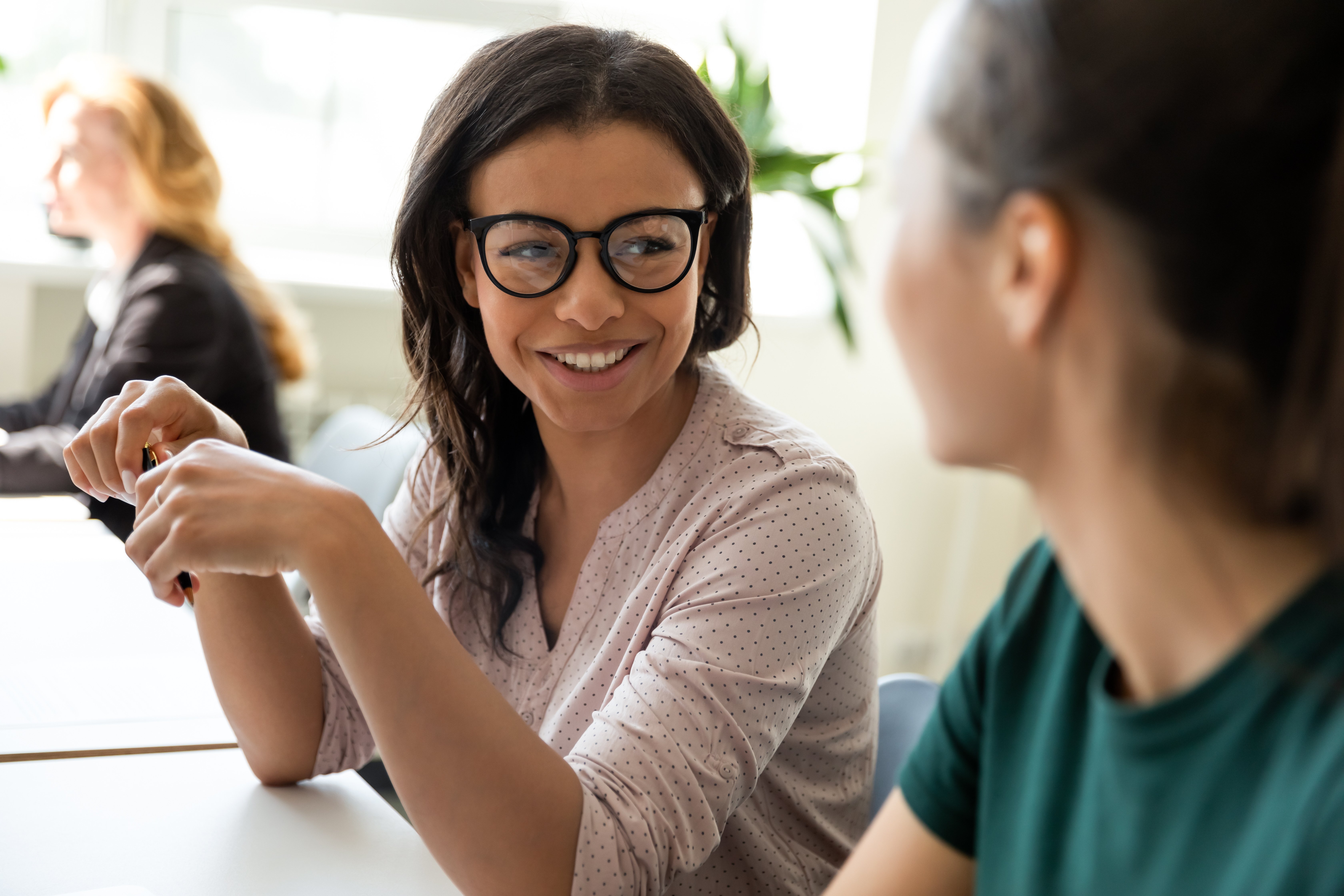 Lächelnde Büroangestellte spricht mit einem Kollegen über ihre Zukunftspläne
